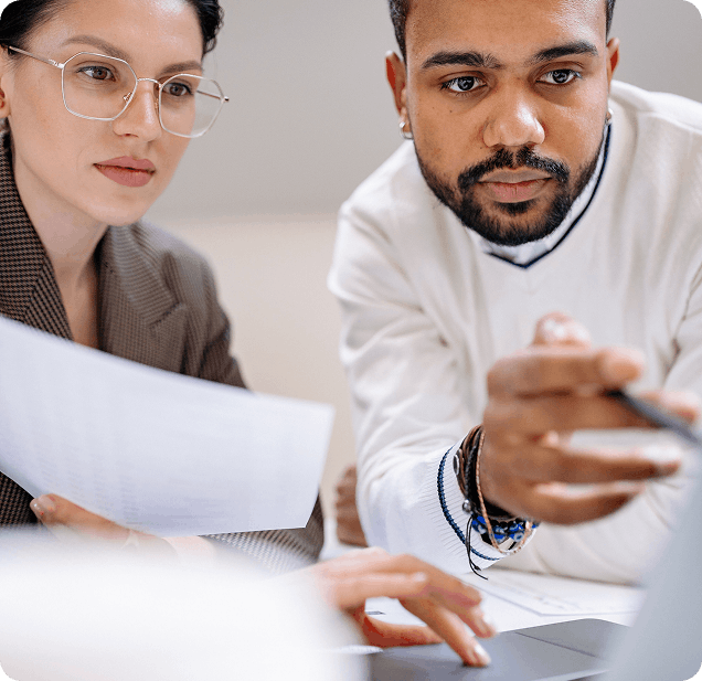 Un homme et une femme collaborant attentivement sur un document et un écran de portable.